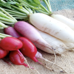 Lobak putih merah segar di atas talenan dengan daun hijau, menunjukkan sumber oksalat alami.”