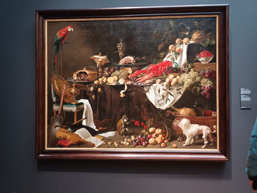 A richly composed still life displays food, musical objects, and carefully observed textures