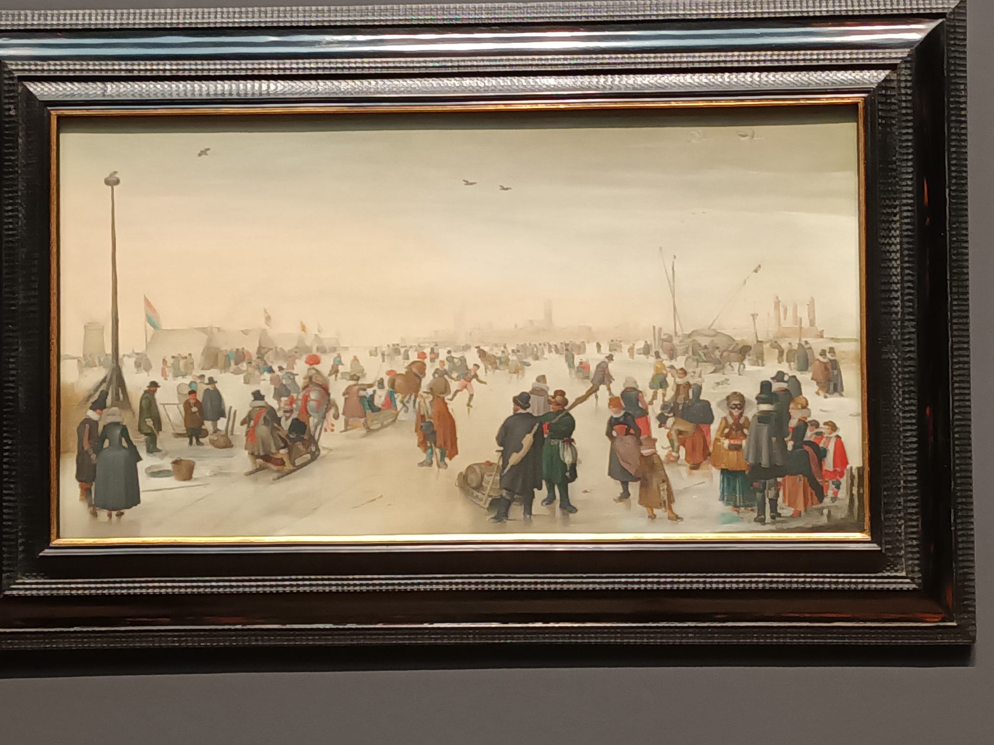 A winter landscape depicts people gathering across a broad, snow-covered scene