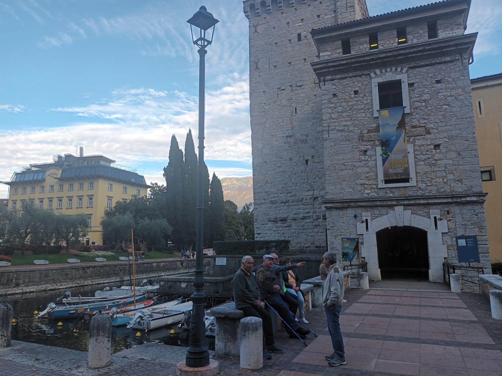 The Rocca di Riva and its boat-filled canal, with a museum banner on the wall